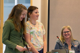 Students and teacher speaking at meeting