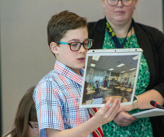 Student in glasses holding up photo